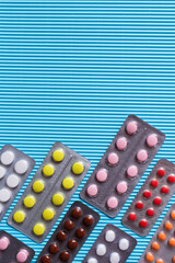 top view of blister packs with different pills on blue textured background.