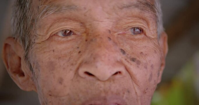 Asian male farmer's eyes who is the long life native 98 years, white hair, freckled skin, still in good health living in a rural farmer's village.