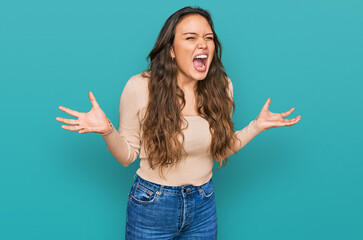 Young hispanic girl wearing casual clothes crazy and mad shouting and yelling with aggressive...