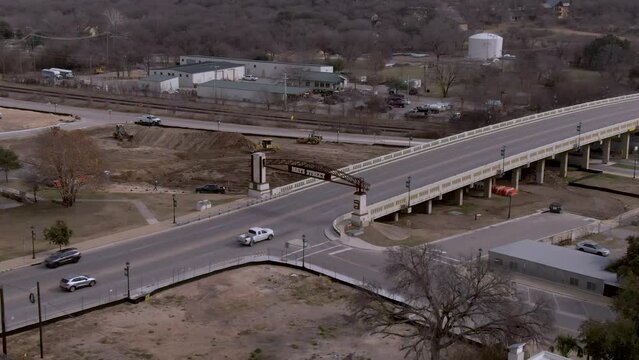 Aerial follow shot of cars passing over Mays Street bridge near downtown Round Rock, Texas.