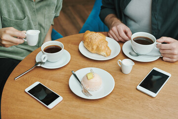 Fototapeta na wymiar Above view of unrecognizable man taking photo of black coffee and croissant on table in cafe, bloggers lifestyle concept