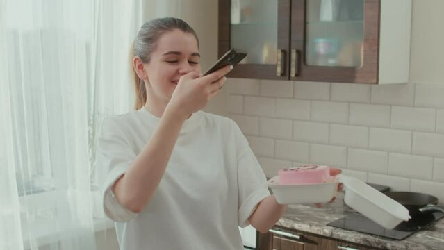 A woman takes a picture on a smartphone of a cake in a gift box