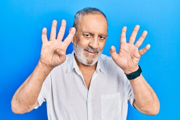 Handsome senior man with beard wearing casual white shirt showing and pointing up with fingers...