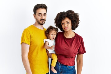 Interracial young family of black mother and hispanic father with daughter relaxed with serious...