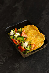 Healthy food delivery concept. Chicken schnitzel with Greek salad in an eco paper container on a...