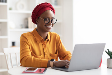 Happy stylish black lady freelancer working on laptop
