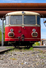Frontal view of a historic red railcar called “Schienenbus“ on a side track of a ruined...