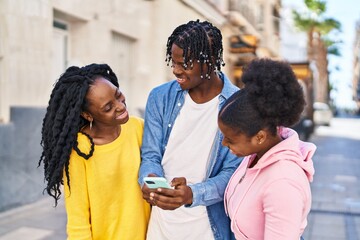 African american friends standing together using smartphone at street