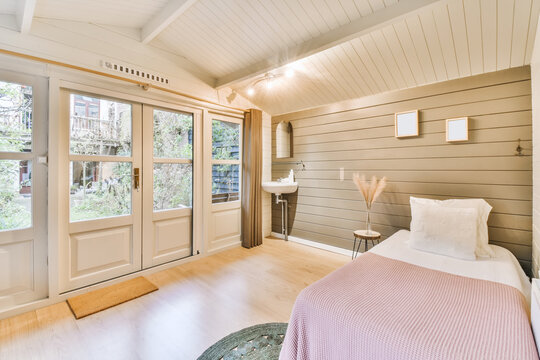 Spacious bedroom with comfortable bed on wooden wall with sink