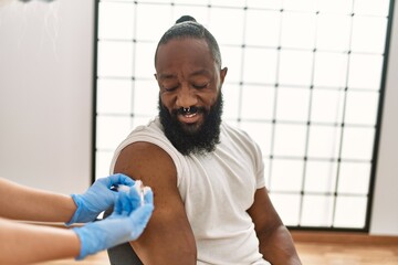 Hands of nurse woman injecting covid-19 vaccine to african amercian man at the clinic.