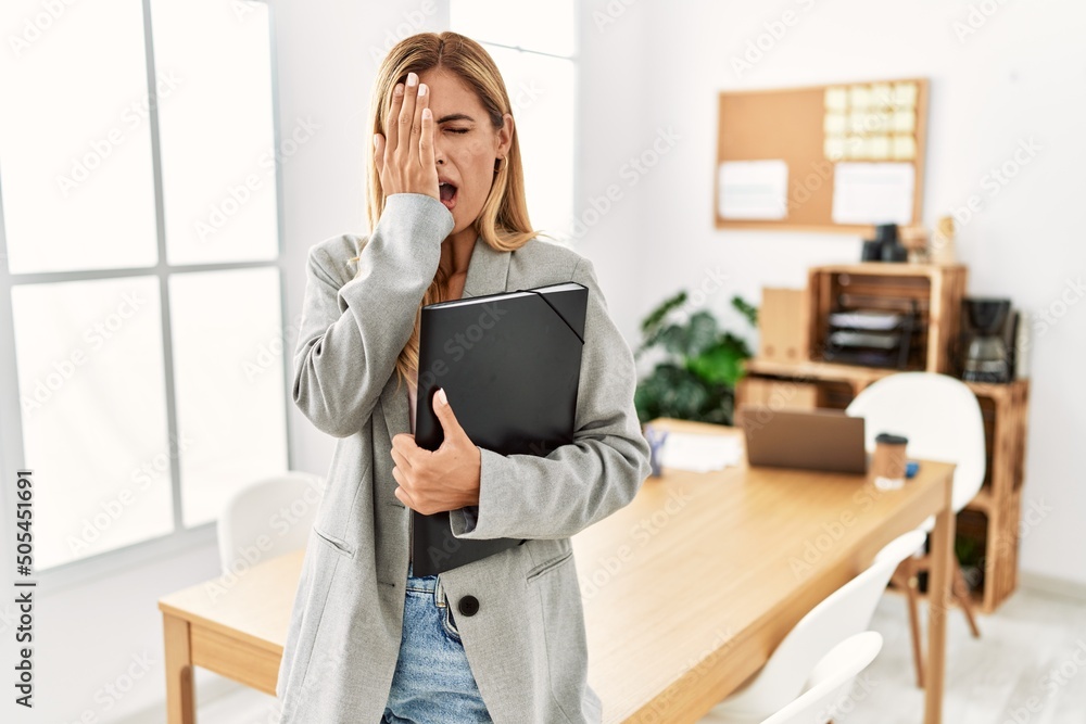 Wall mural Blonde business woman at the office yawning tired covering half face, eye and mouth with hand. face hurts in pain.