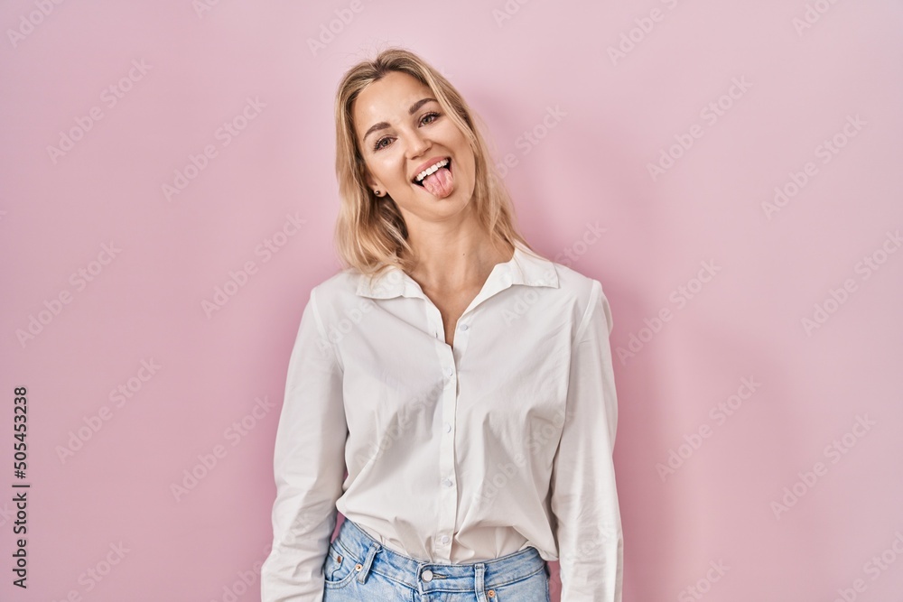 Sticker Young caucasian woman wearing casual white shirt over pink background sticking tongue out happy with funny expression. emotion concept.