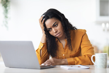 Upset black lady freelancer working on laptop at home