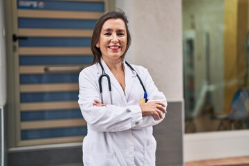 Middle age woman wearing doctor uniform smiling confident standing at street