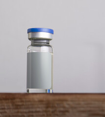 Medical vial for injection with a blank label against a white wall