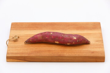 Closeup fresh sweet potato on wooden cutting board and isolated on white background