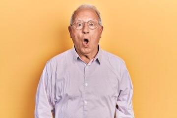 Senior man with grey hair wearing elegant shirt and glasses scared and amazed with open mouth for...