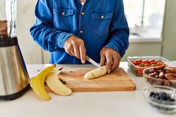 Senior man cutting banana at kitchen