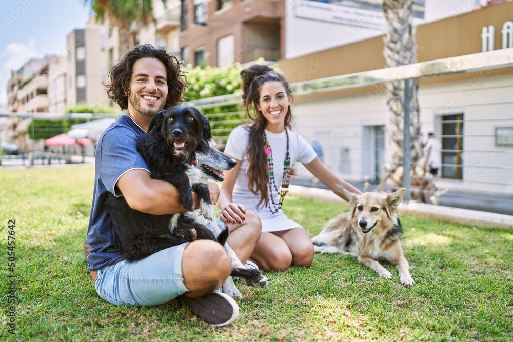 Sticker Man and woman couple smiling confident sitting on herb with dogs at park