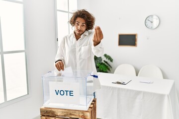 Young hispanic man voting putting envelop in ballot box doing italian gesture with hand and fingers...