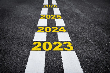 Number of 2023 to 2026 on asphalt road surface with marking lines, happy new year concept