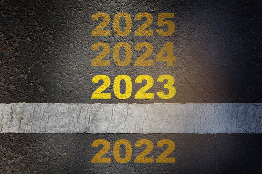 Number 2022 stand out from 2022 to 2025 on asphalt road surface with white starting lines. Beginning happiness new year concept and keep moving idea