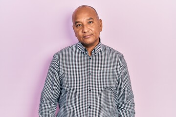 Middle age latin man wearing casual clothes relaxed with serious expression on face. simple and...