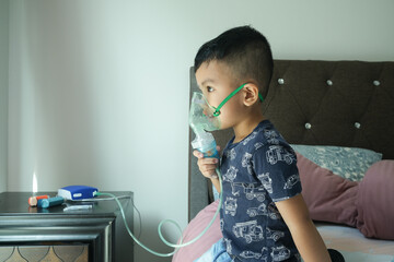 A picture of a boy using home nebulizer machine for treating asthma, bronchitis and illness related...