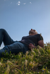 Naklejka na ściany i meble Portrait of adult man lying on grass against sky