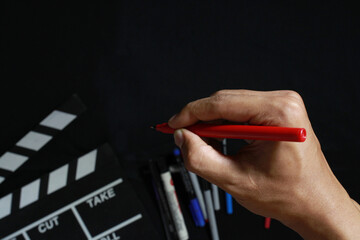 Man holding pen  on black background, cinema concept