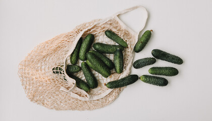 fresh cucumbers in a reusable string bag isolated on white background top view. Zero waste concept