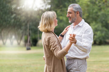 Elderly Caucasian couple dancing happy together. Mature man and woman together in outdoors park. lifestyle senior concept.