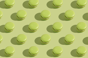 Hard light pattern of a green macaron pastry photographed on light green surface