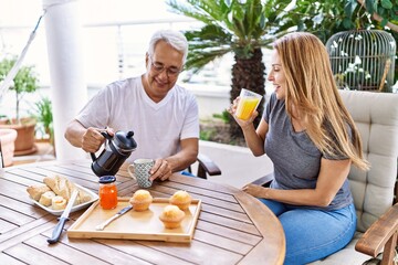 Middle age hispanic couple smiling happy having breakfast at the terrace.
