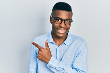Young african american man wearing casual clothes and glasses smiling cheerful pointing with hand...