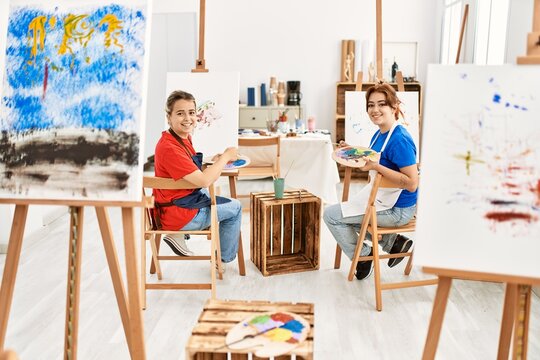 Two artist student women smiling happy painting at art school.