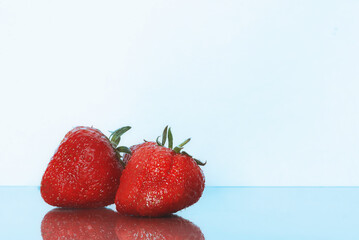 Strawberries isolated. Strawberry with leaf isolate. Two whole strawberries on white and blue. Side view.