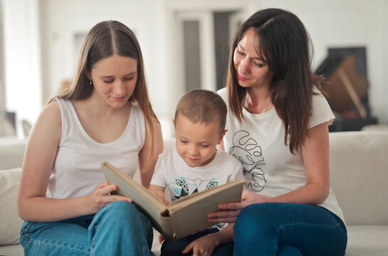 mother and two children on the sofa at home look at a picture book