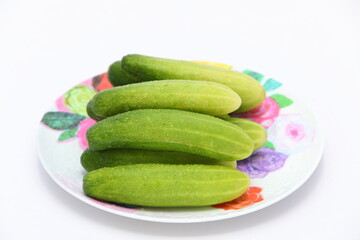 Closeup fresh cucumbers on plate and isolated on white background
