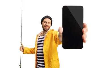 Smiling fisherman in a yellow raincoat holding a fishing rod and showing a smartphone