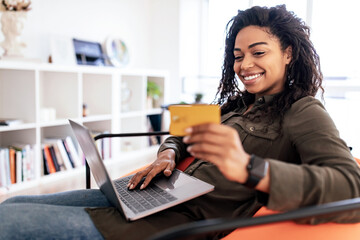 Happy woman holding debit credit card, using laptop pc