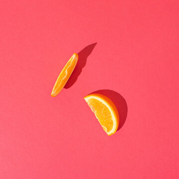 Orange slace on vibrant pink background.  Minimal summer fruit or organic food concept.