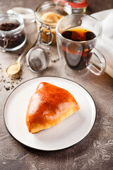 Sweet pies or buns made from yeast dough on platter and glass of tea