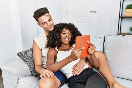 Man and woman couple using touchpad hugging each other at home