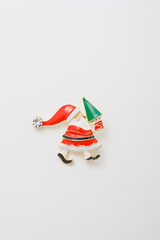 Metallic cute brooch in shape of Santa Claus holding Merry Christmas tree, pin on white background, bijouterie, jewelry close up