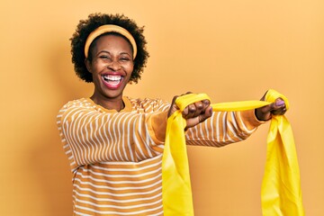 Young african american woman wearing sportswear and arm band smiling and laughing hard out loud...