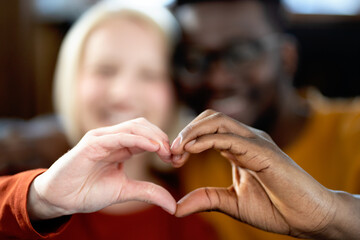Multi-ethnic couple showing a heart symbol made by their hands. Diversity concept