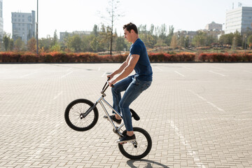 Teenage BMX rider is performing tricks in skatepark