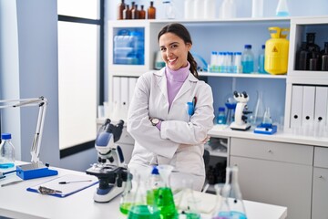 Young brunette woman working at scientist laboratory happy face smiling with crossed arms looking at the camera. positive person.