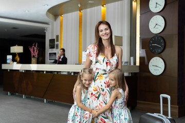 Mother with twin daughters hugging at the hotel reception